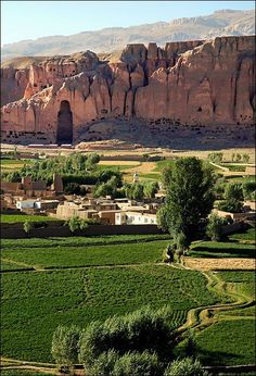 the landscape is full of green grass and mountains in the distance are rocky cliffs, with houses on either side