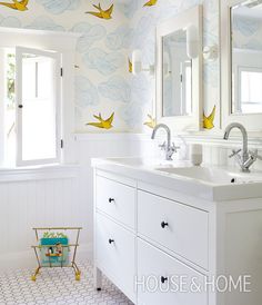 a bathroom with white cabinets and blue birds on the wall above the sink, along with two mirrors