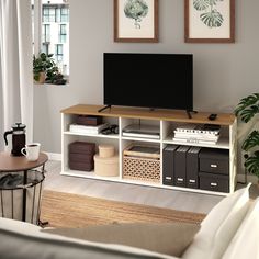 a flat screen tv sitting on top of a wooden shelf in a living room next to a window