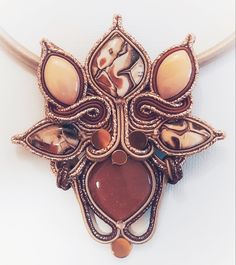 a necklace is adorned with an intricately designed pendant and bead work on a leather cord