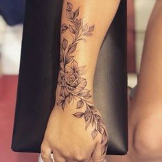 a woman's hand with a flower tattoo on her wrist and the other arm