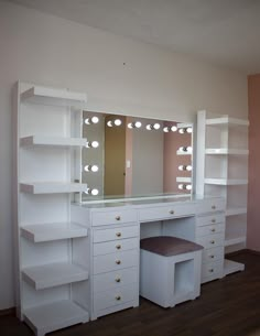 a white vanity with lights on it and a stool