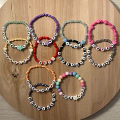 several bracelets are arranged on a wooden board with beads and eyeballs in different colors