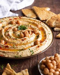 hummus and pita chips on a table with crackers in the foreground