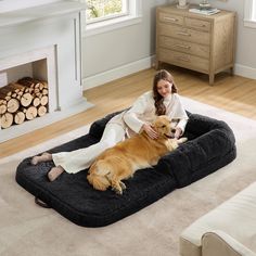 a woman sitting on a dog bed with her golden retriever