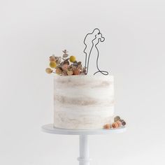 a white cake topped with a single layer frosted cake covered in candies and an outline of a kissing couple