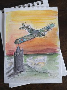 a drawing of an airplane flying over a castle on top of a wooden table next to a pen and paper