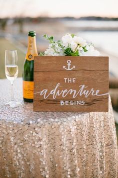 a wooden sign sitting on top of a table next to a wine glass and bottle