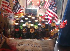 an assortment of beer bottles in a bucket with american flags on the window sill