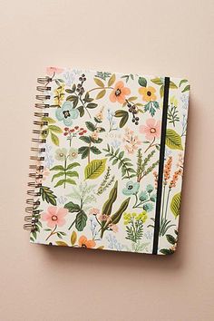 an open notebook with flowers and leaves on the cover, next to a pink wall