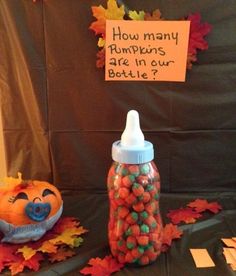 a bottle with candy in it sitting next to a sign that says how many pumpkins are in our bottle?