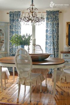 a dining room table with chairs and a chandelier hanging from the ceiling above it