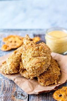 some fried food is sitting on a napkin next to a jar of mustard and two small crackers