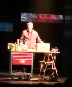 a man standing at a table with tools on it in front of a tv screen