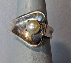 Sigi Pineda Pearl Ring Signed vintage Pineda Taxco Mexico ring. Ring is a classic Mid Century Modern design crafted out of fine Mexican silver with 7mm prong set Pearl. Ring is fully hallmarked and will arrive gift boxed. * HALLMARKS Sigi Tasco, Sterling, Mexico, Eagle 3 mark. * SIZE 5, ring could be resized by any good jeweler. Width of band is 16mm and ring weighs 6 Grams. * CONDITION In very good condition. Please use all pictures as part of item's description. * MATERIALS Sterling Silver, Pe Vintage Solitaire Signet Ring, Vintage Adjustable Pearl Ring For Wedding, Vintage Jewelry With Polished Round Band, Vintage Jewelry With Polished Finish Round Band, Vintage Pearl Open Ring For Anniversary, Vintage Open Ring For Anniversary, Vintage Sterling Silver Open Band Jewelry, Vintage Adjustable Rings With Polished Finish, Vintage Concave Jewelry With Polished Finish