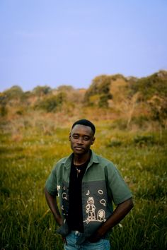 a man standing in the grass with his hands on his hips and looking at the camera