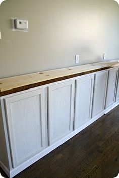 an empty room with white cabinets and wood flooring