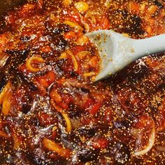 a wooden spoon is stirring some food in a pot filled with oil and seasoning