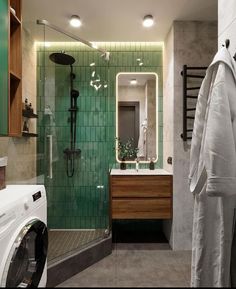 a washer and dryer in a bathroom with green tiles on the shower wall