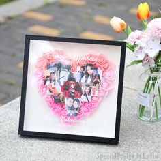 a vase filled with flowers next to a heart shaped photo frame on a stone wall