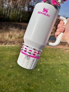 a person holding a white and pink coffee mug in their hand with the word stanley on it