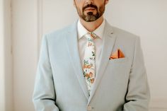 a man wearing a suit and tie with his hands in his pockets looking at the camera