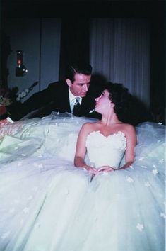 a man and woman in wedding dresses sitting next to each other