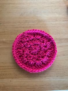 a pink crocheted dishcloth sitting on top of a wooden table