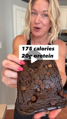 a woman holding up a piece of cake with chocolate chips on it that says 75 calories 20g protein