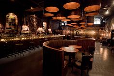 a dimly lit bar with round tables and stools