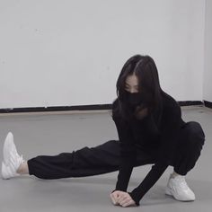 a woman in black is stretching on the floor with her hands behind her head and wearing white sneakers