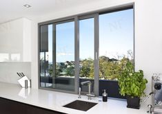 a kitchen with a sink, stove and large window overlooking the trees outside in front of it