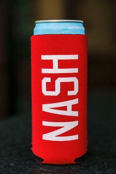 a red can cooler sitting on top of a black table next to a blue and white cup