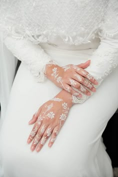 a woman wearing white gloves and holding her hands on the back of her dress,