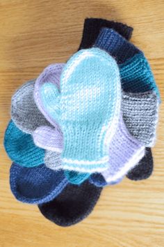 several knitted hats sitting on top of a wooden table