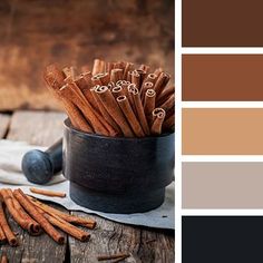 some cinnamon sticks are in a black cup on a wooden table with color swatches