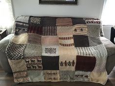 a couch covered in a multi - colored patchwork blanket on top of a hard wood floor