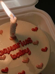 a birthday cake with hearts on it and a lit candle that says happy valentine's day