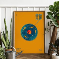 an orange poster with gold fish on it in front of some potted plants and a watering can