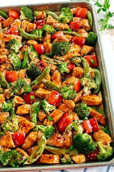 a pan filled with chicken, broccoli and peppers