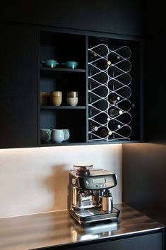 a coffee maker sitting on top of a counter next to a shelf filled with cups