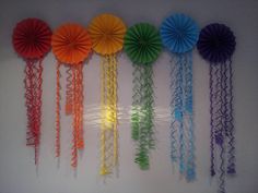 there are many different types of paper fans hanging on the wall with string attached to it