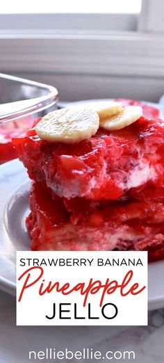 a stack of strawberry banana pineapple jello on a white plate with a bowl of fruit in the background