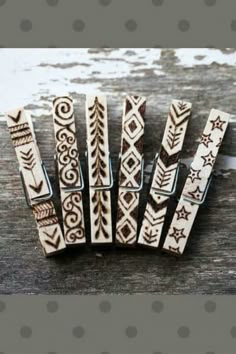 four wooden clips with designs on them sitting on top of a piece of wood next to a