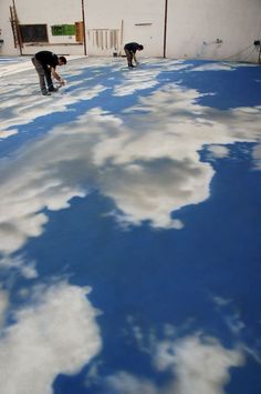 two men are painting the ground with blue and white paint on it in an empty building