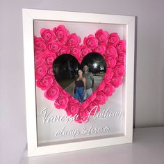 a white frame with pink roses in the shape of a heart and an image of a man and woman