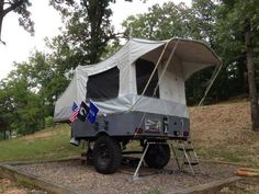 an off - road camper is parked on the side of a hill with trees in the background