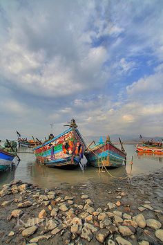 there are many boats that are sitting in the water near each other on the shore