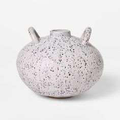 a white vase with black speckles on it