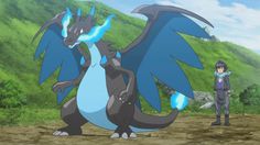 two people standing next to each other in front of a green hill with a blue and white dragon on it